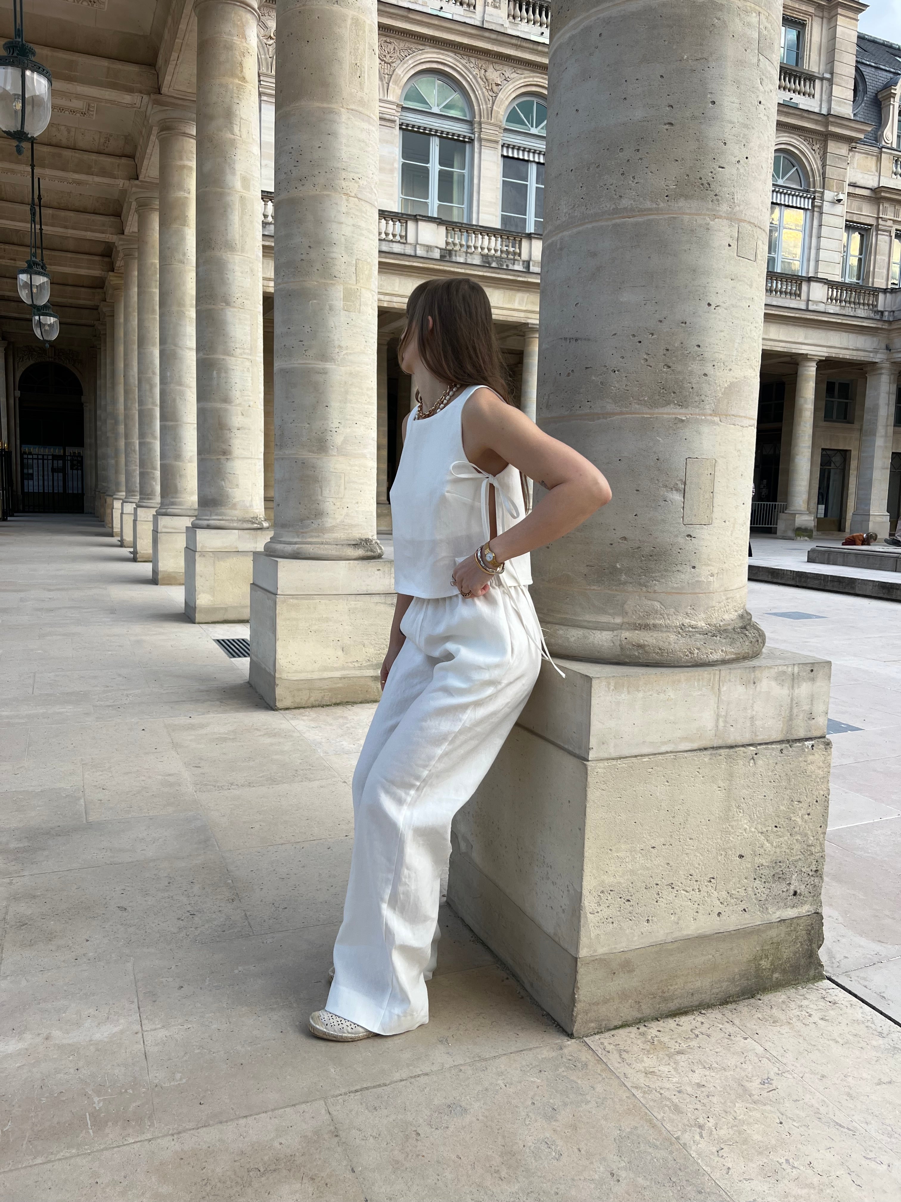 haut douceur en lin blanc noué porté en extérieur avec pantalon en lin vu de trois quarts