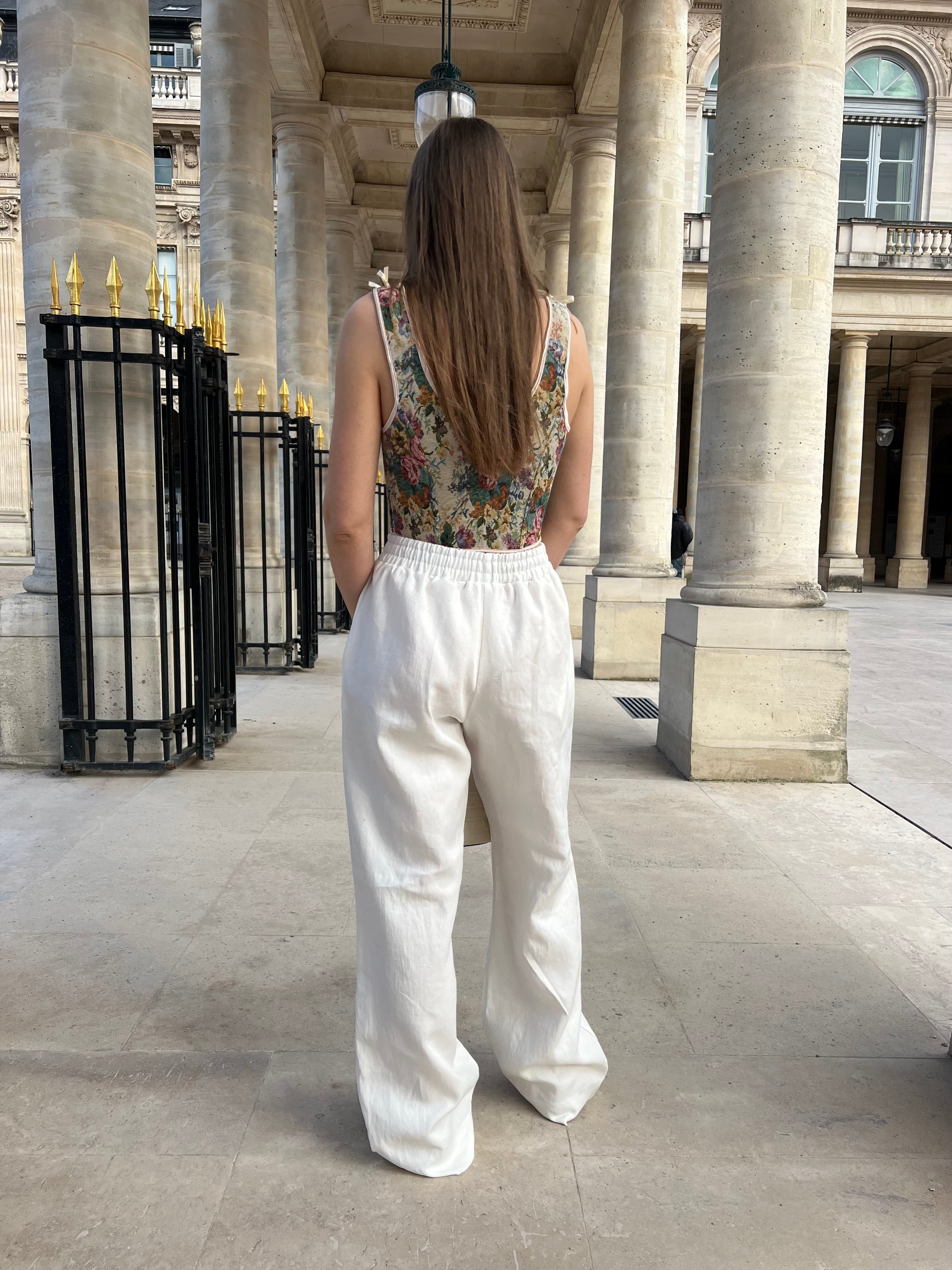 pantalon leo en lin blanc porté en extérieur avec corset et sac vue de dos