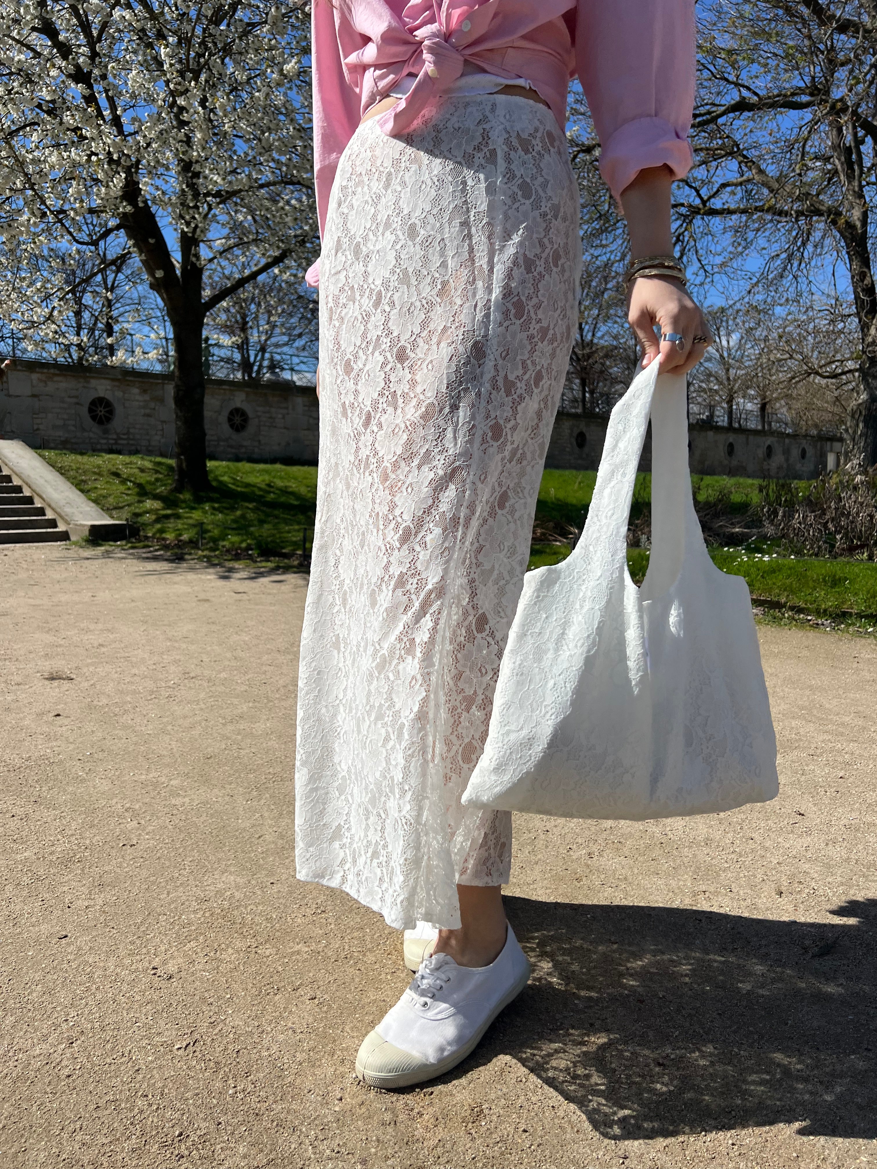 sac mael en dentelle blanche porté à la main en extérieur avec jupe jeanne en dentelle blanche assortis