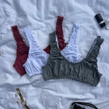 lot de 3 brassières rosalie en jersey pointelle gris, blanc et framboise, posé sur un drap.