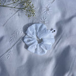 chouchou en broderie anglaise posé sur un drap