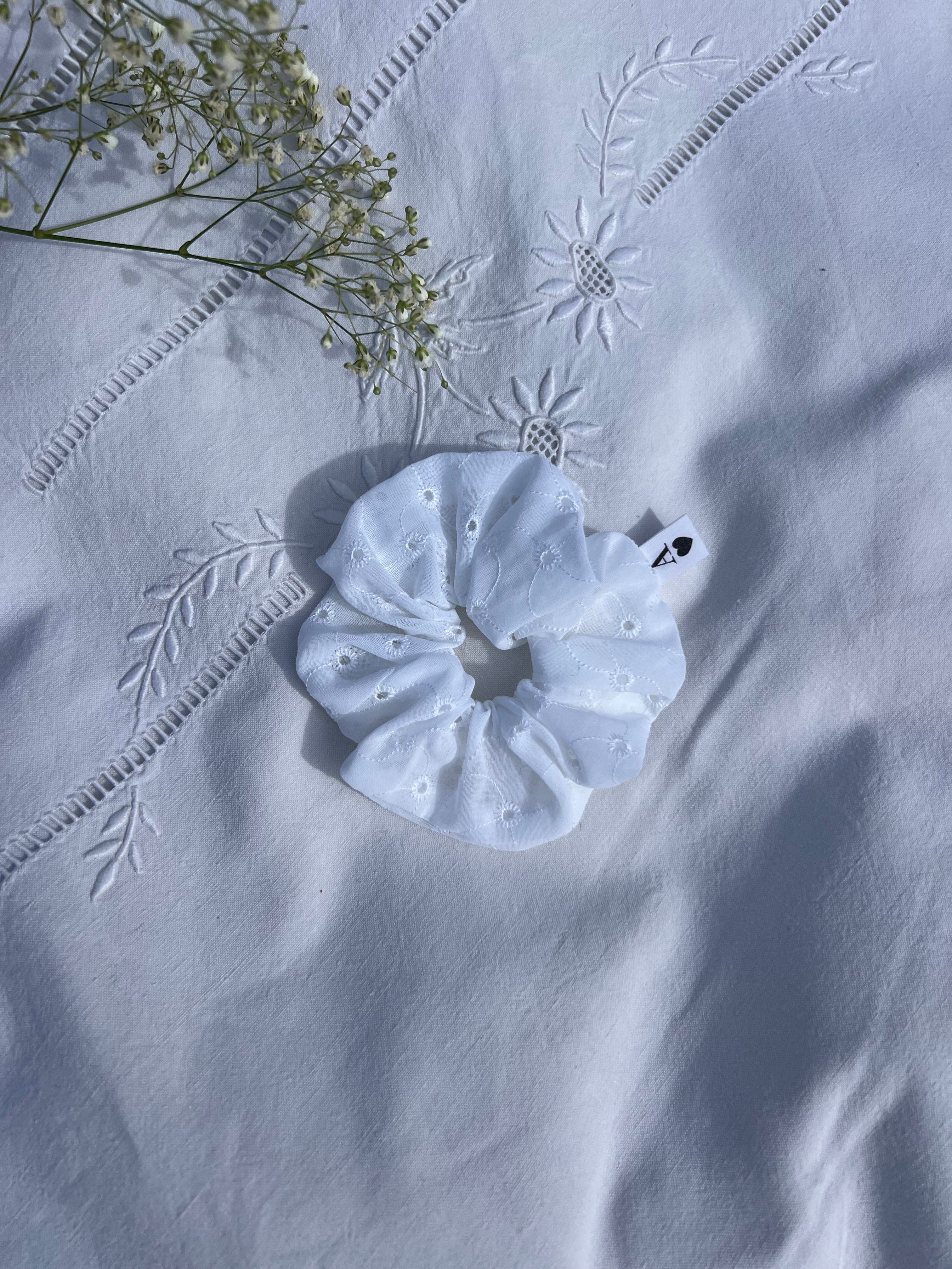 chouchou en broderie anglaise posé sur un drap