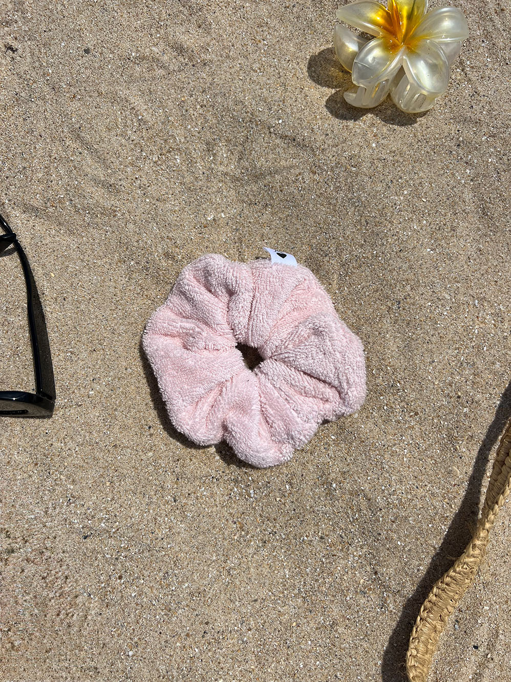 chouchou en éponge rose posé sur le sable