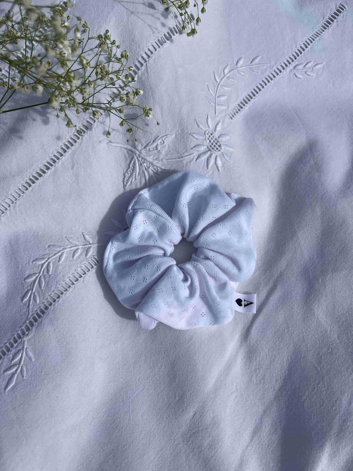 chouchou en jersey pointelle blanc posé sur un drap