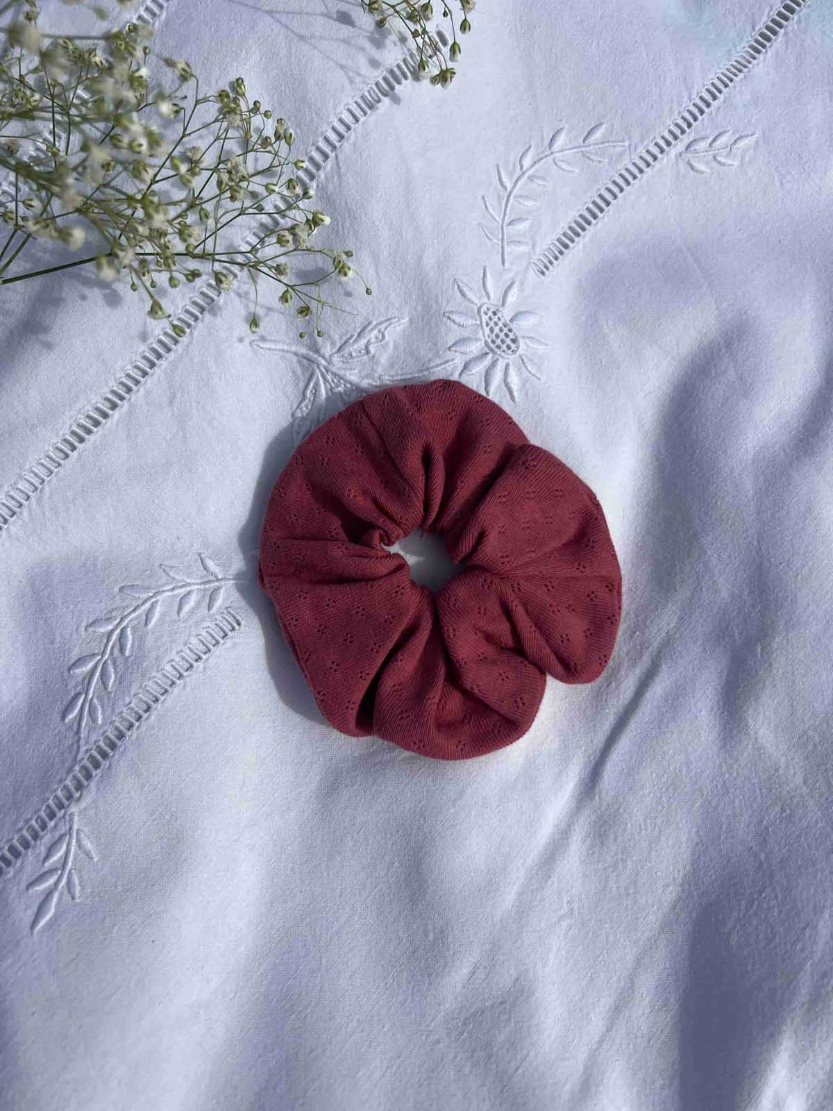 chouchou en jersey pointelle framboise posé sur un drap