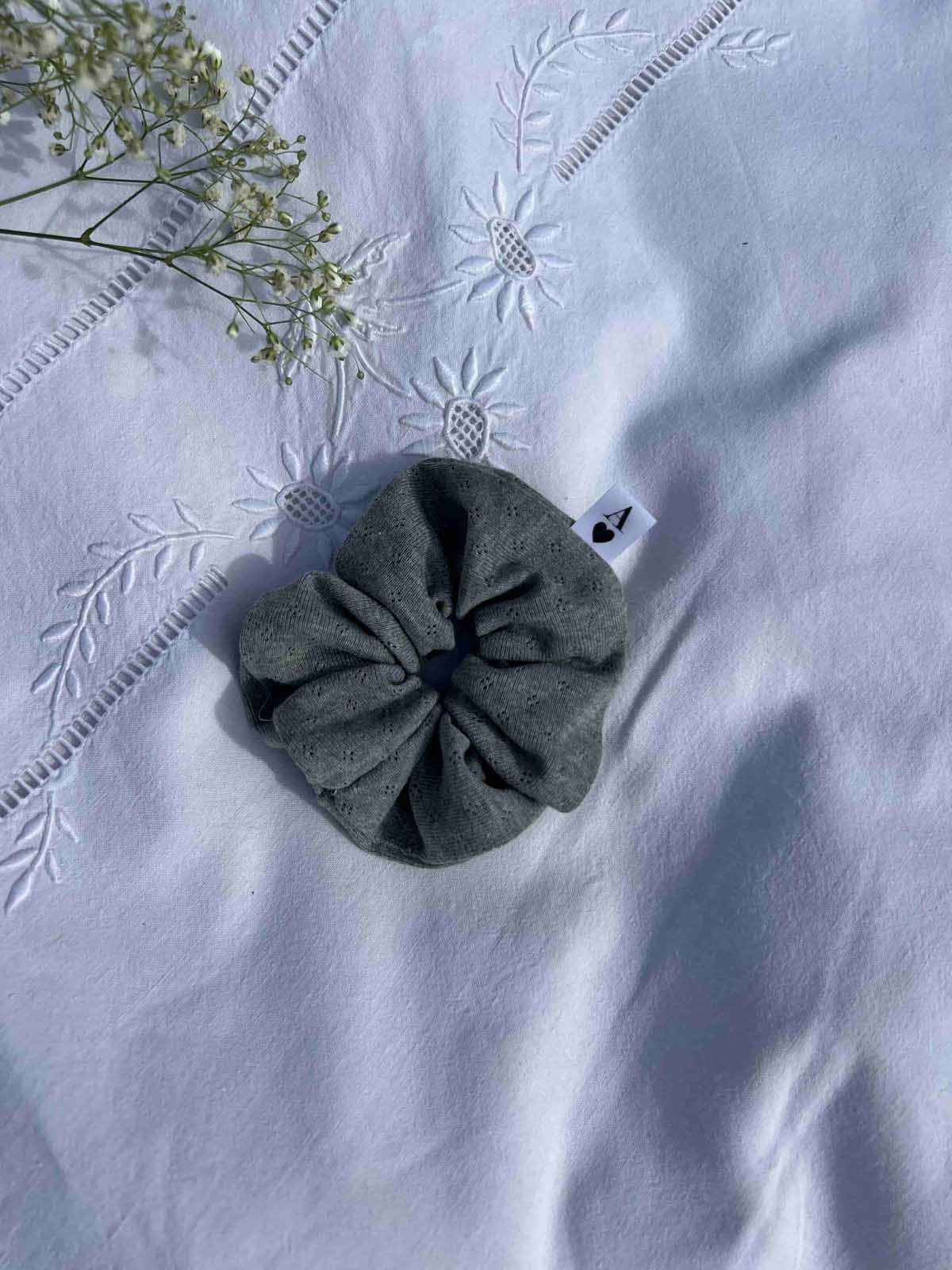 chouchou en jersey pointelle gris posé sur un drap