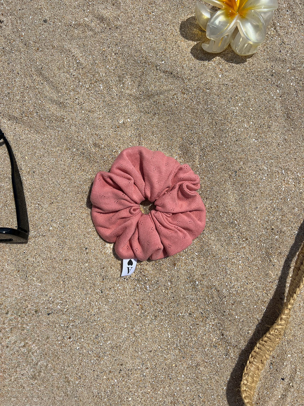 chouchou en jersey pointelle corail posé sur le sable