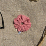 chouchou en jersey pointelle corail posé sur le sable