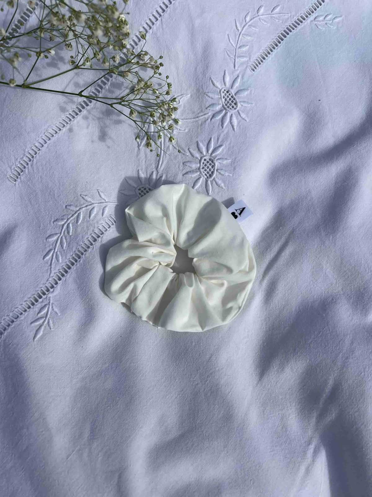 chouchou en popeline blanc posé sur un drap