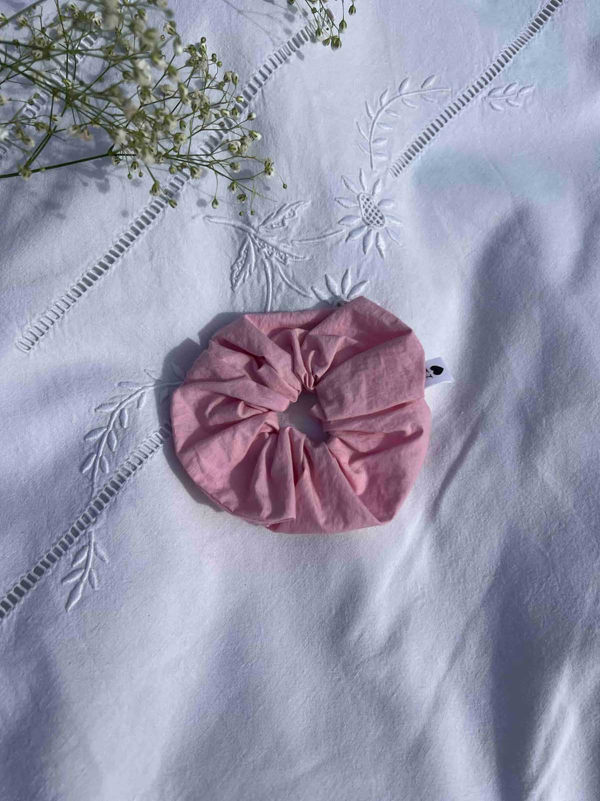 chouchou en popeline rose posé sur un drap