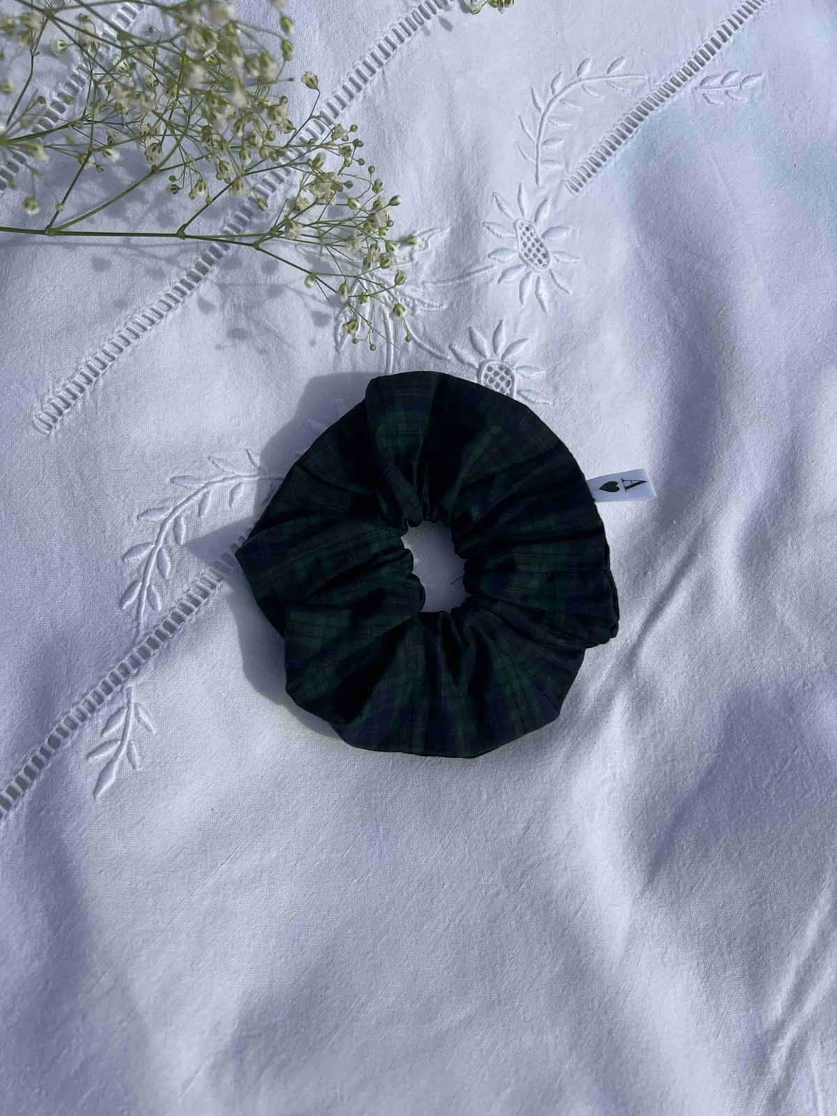chouchou en popeline à carreaux vert et bleu posé sur un drap