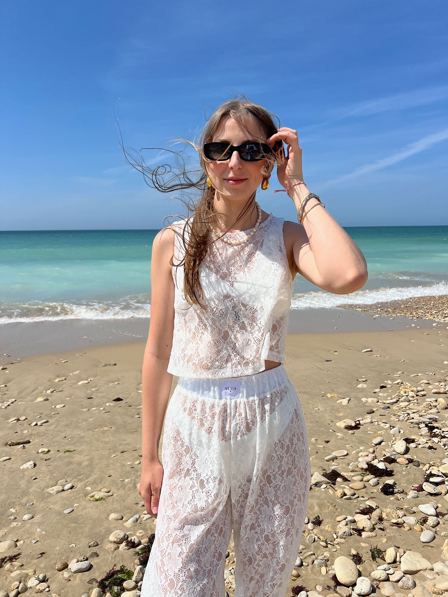 top Douceur en dentelle blanc porté à la plage avec pantalon Léo assortis, vue de face