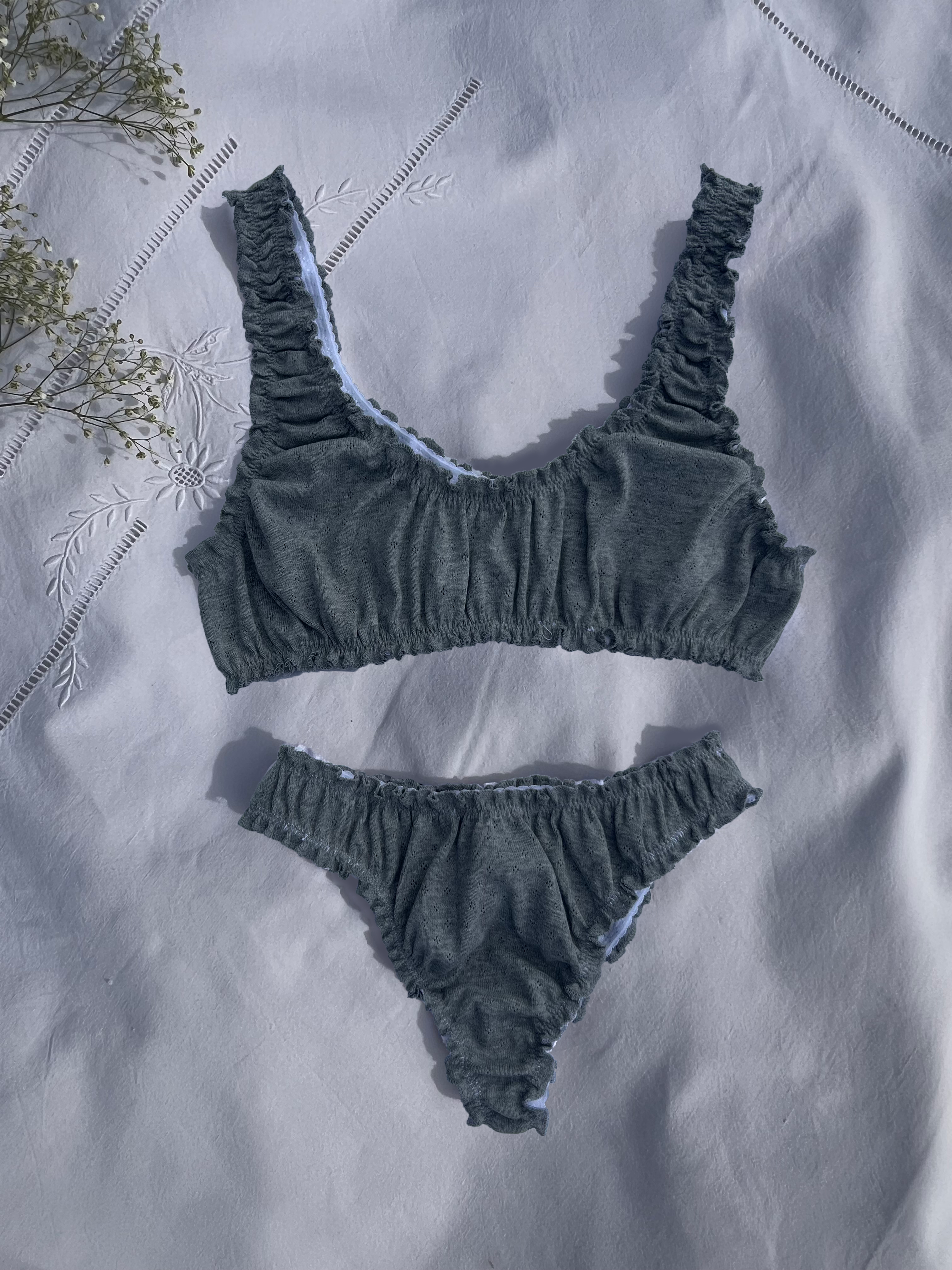 ensemble rosalie brassière et tanga en jersey pointelle gris posé sur un drap