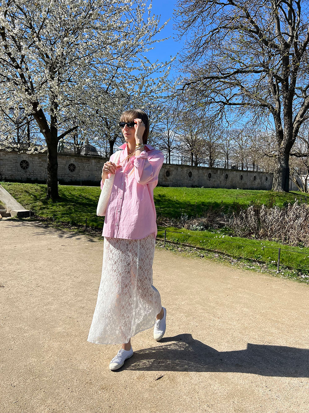 jupe jeanne en dentelle blanche porté en extérieur en marche avec sac en dentelle et chemise gaby en popeline rose