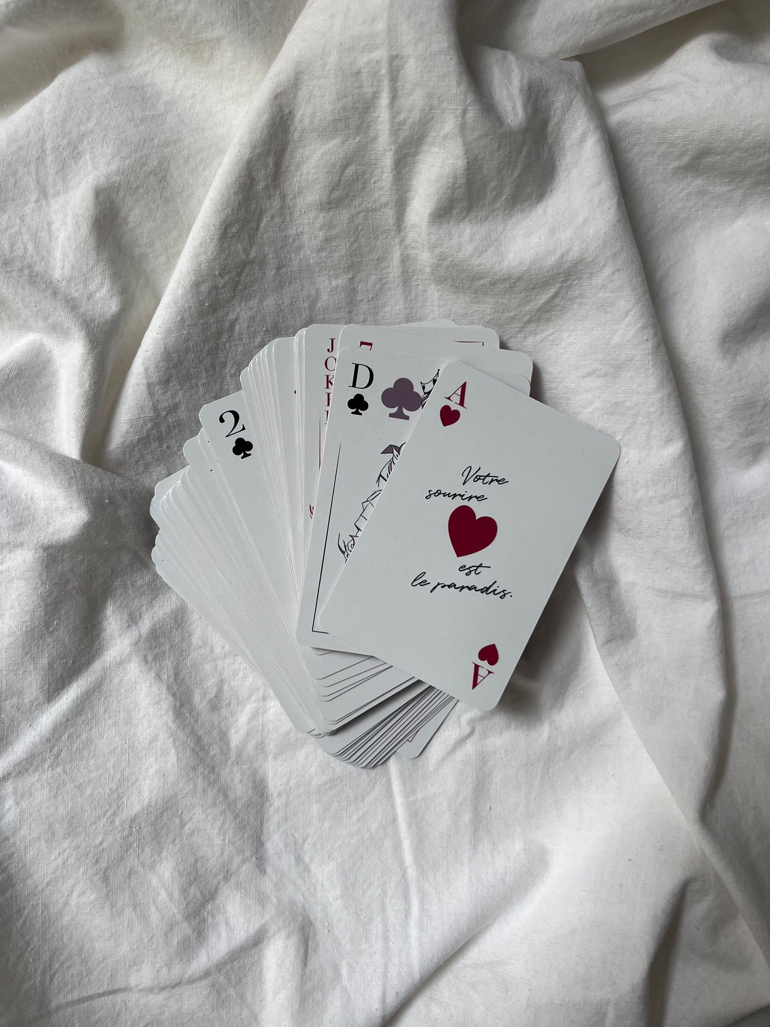 Jeu de cartes ALBA, posé sur le lit, as ce cœur, citation