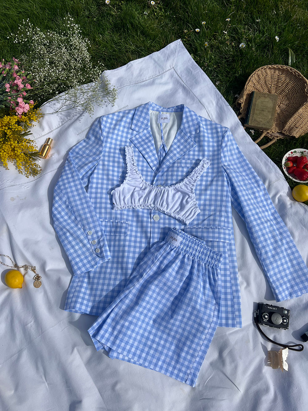 veste nicole en popeline vichy bleu posée sur draps en extérieur avec short lucas assortis et brassière en jersey blanc 