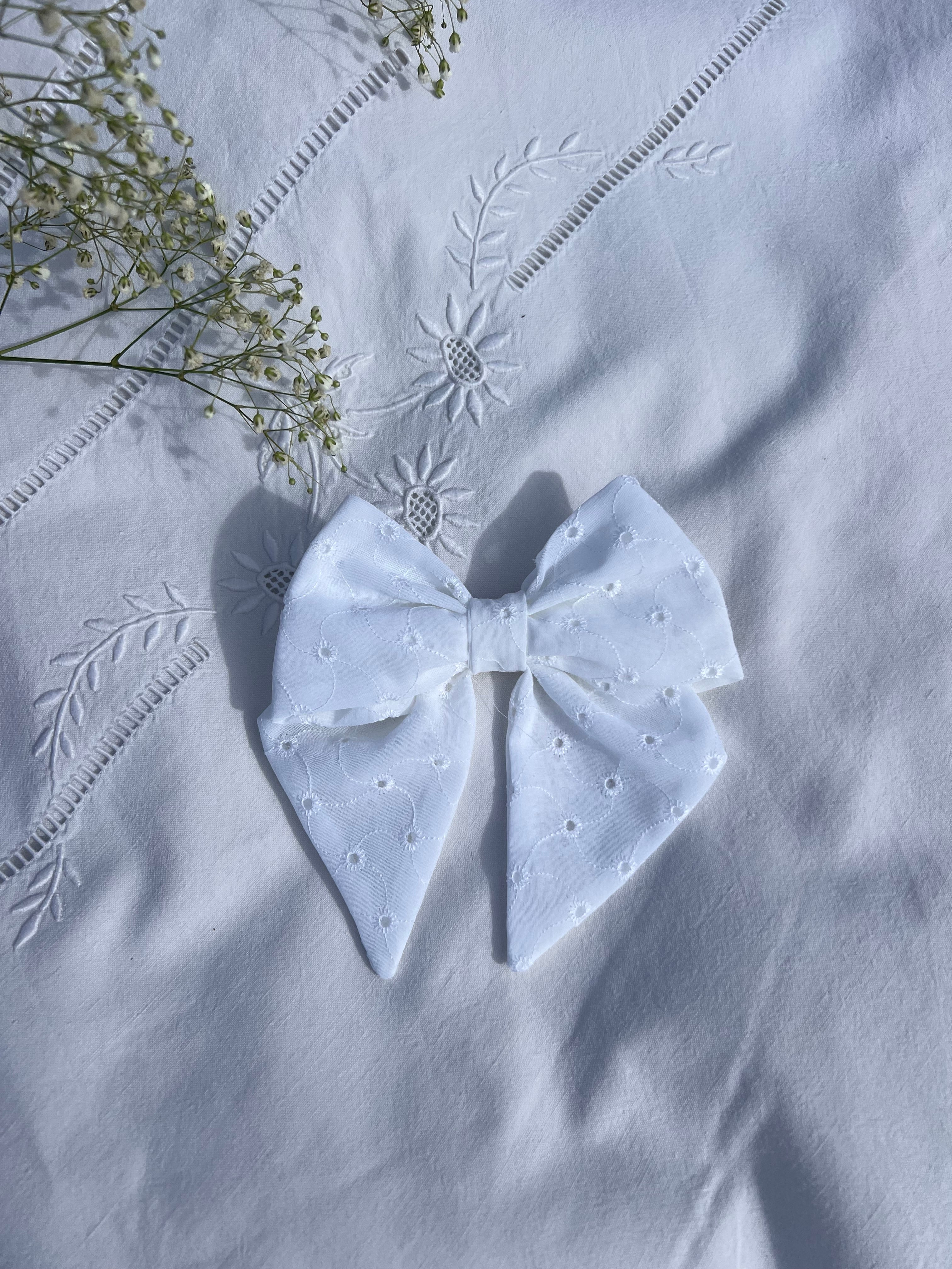 nœud à cheveux enbroderie anglaise posé sur drap
