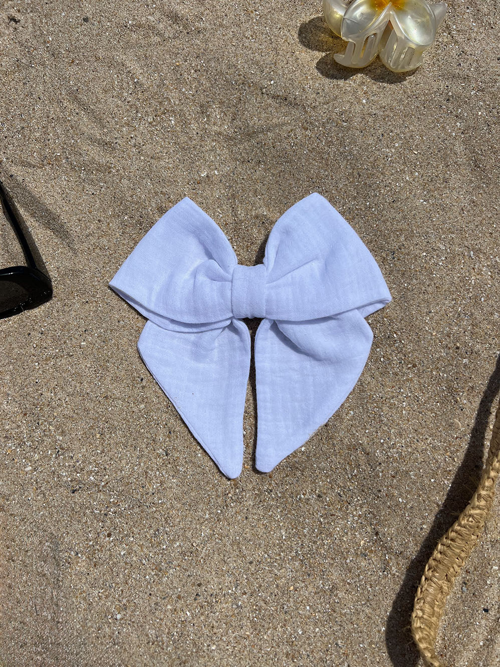 nœud à cheveux en coton gaze blanc posé sur le sable