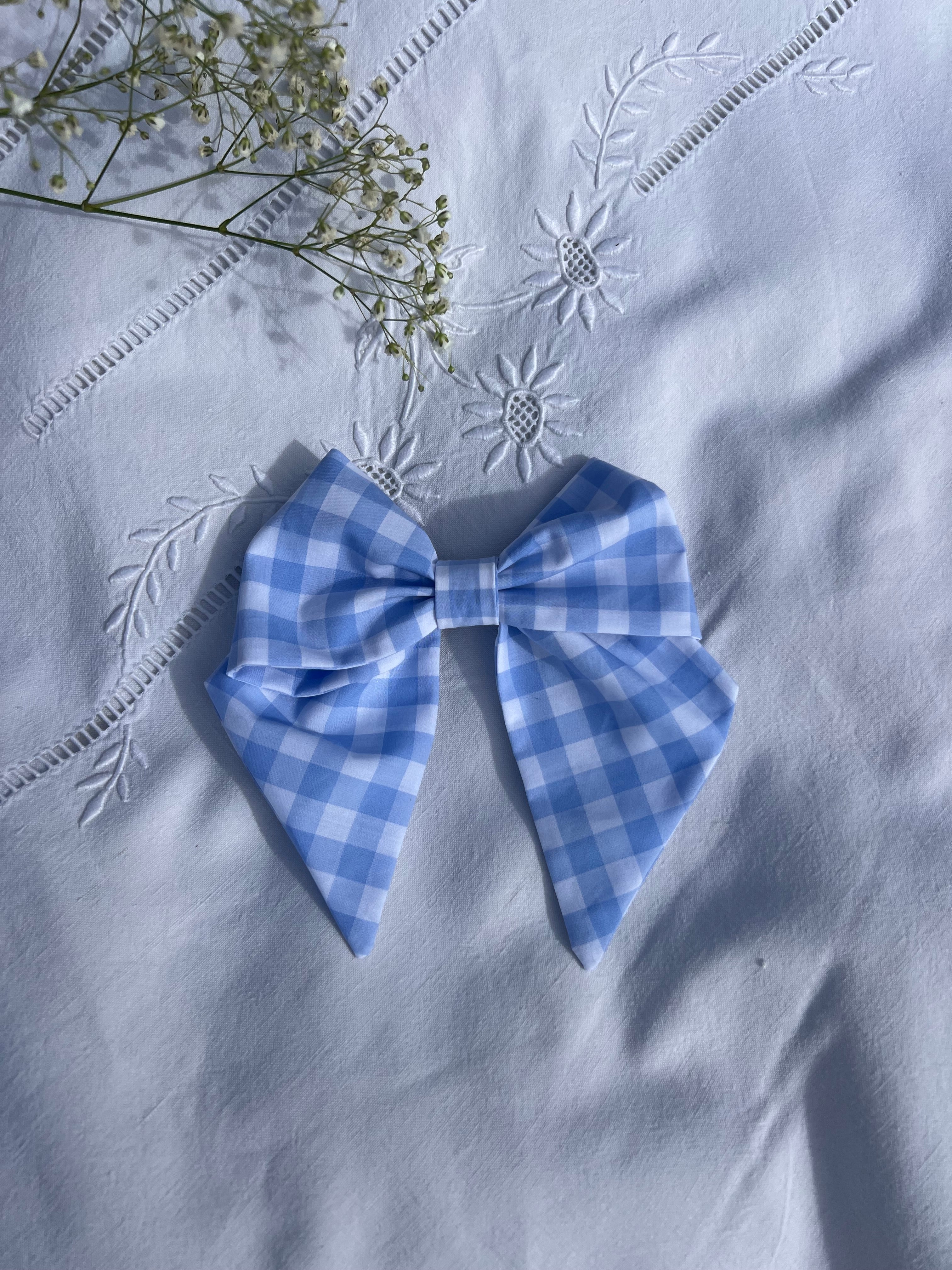 nœud à cheveux en popeline vichy bleu posé sur un drap