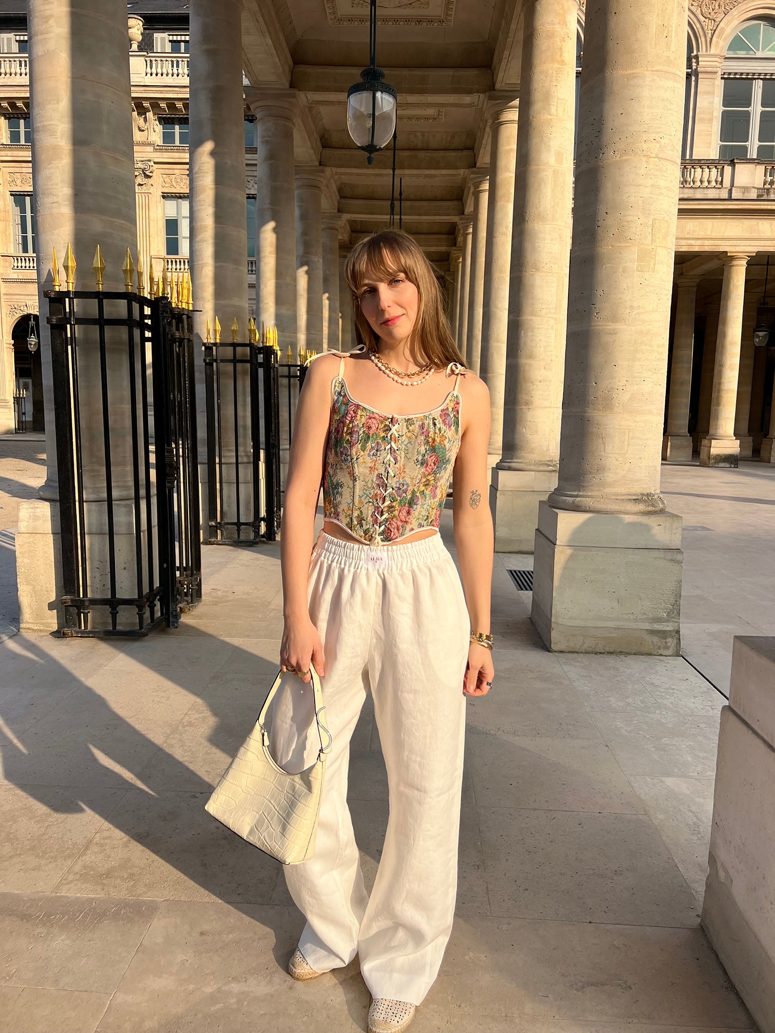 pantalon leo en lin blanc porté en extérieur avec corset et sac pose vue de face