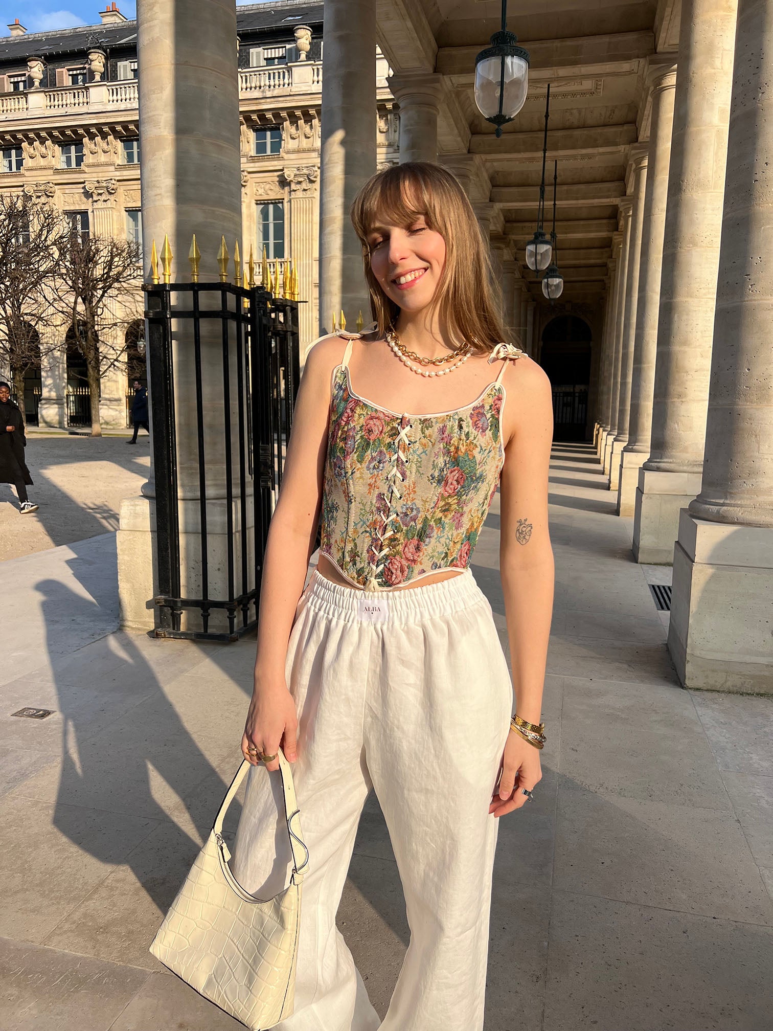 pantalon leo en lin blanc porté en extérieur avec corset et sac vue de face