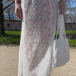 jupe jeanne en dentelle blanche porté en extérieur vue de face en mouvement avec sac en dentelle et chemise gaby en popeline rose nouée