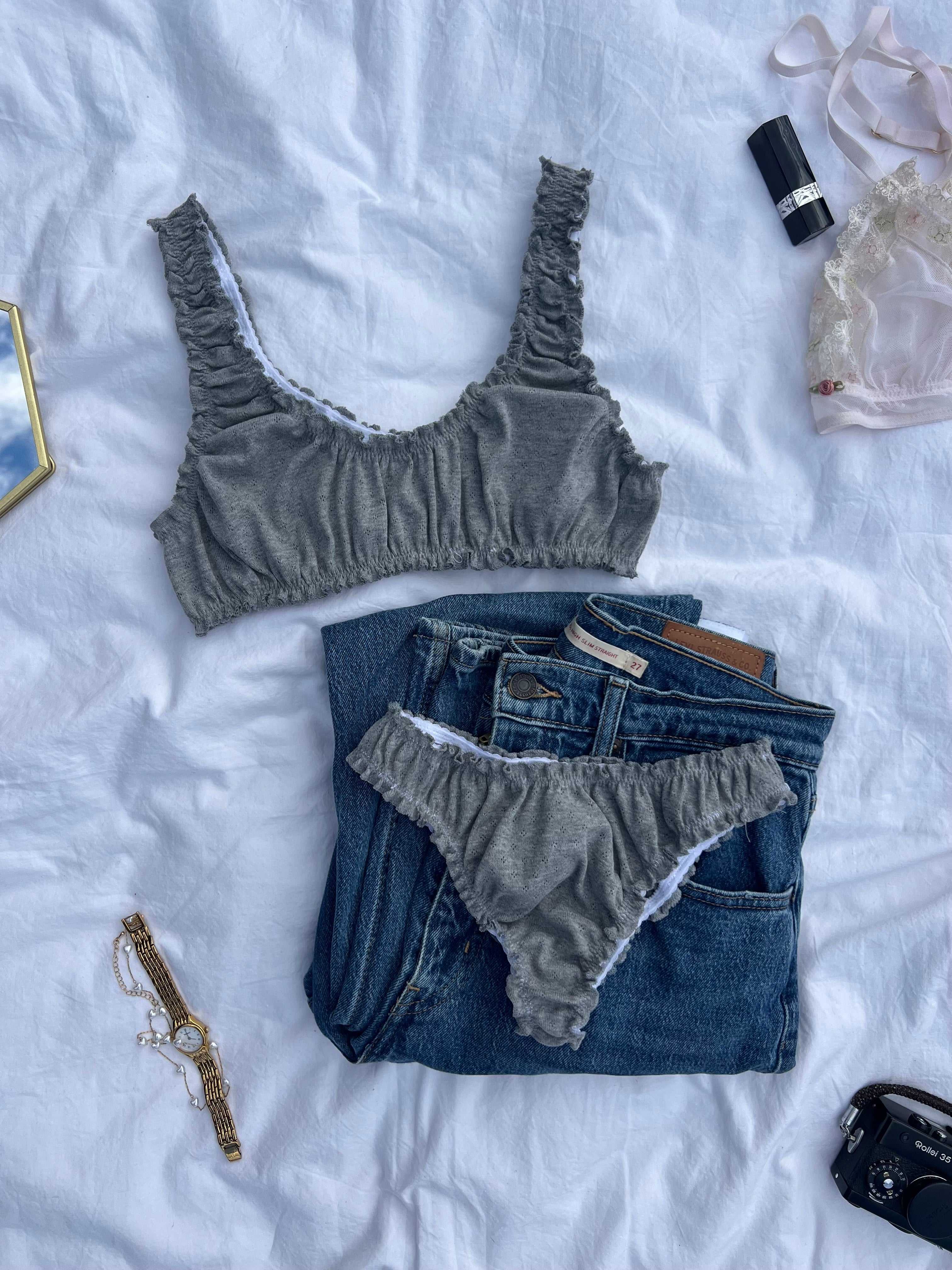 ensemble rosalie en jersey pointelle gris brassière et tanga posés sur un draps avec un jean