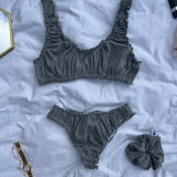 ensemble rosalie brassière et tanga en jersey pointelle gris posés sur un draps avec chouchou assortis