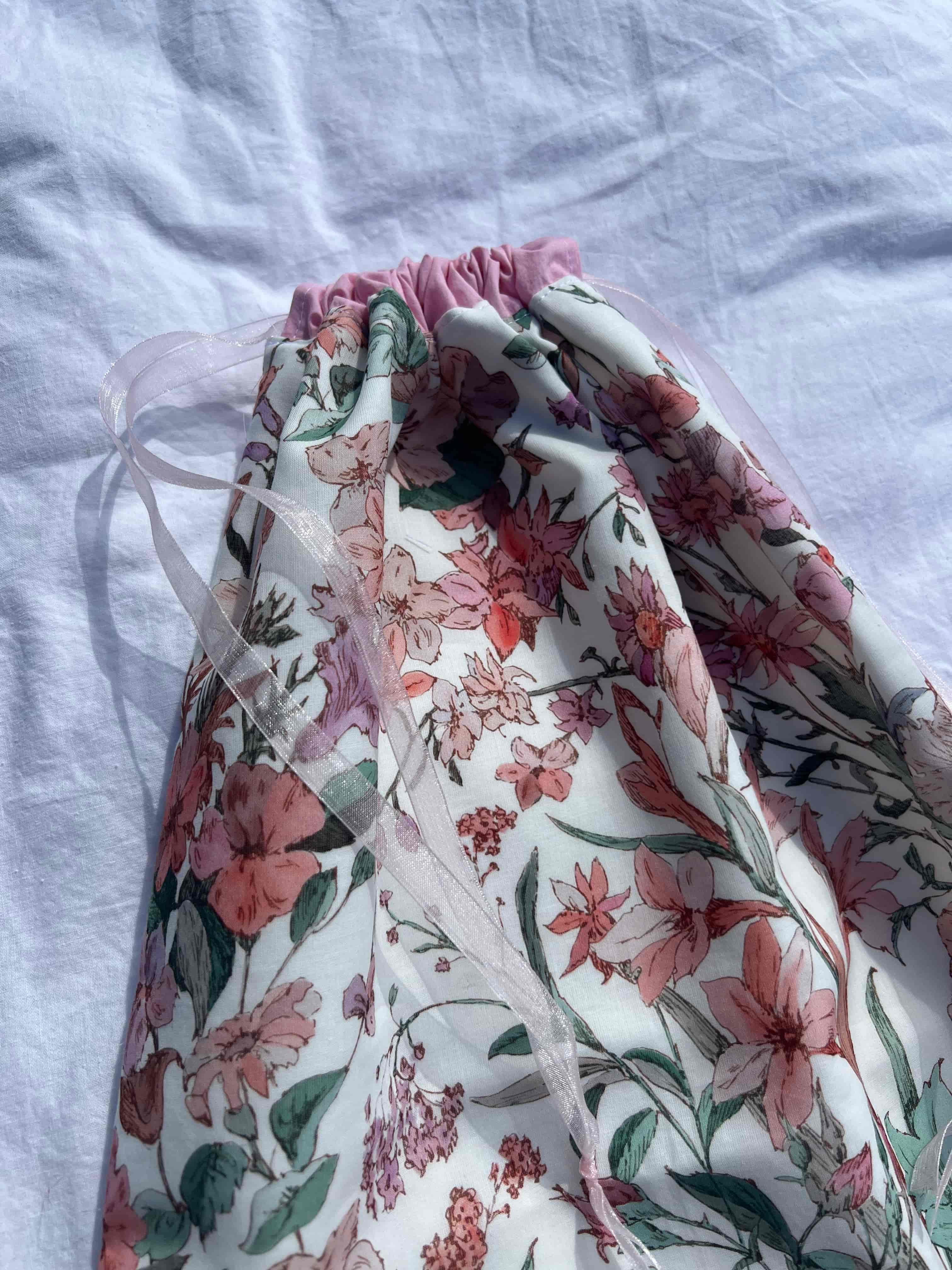 zoom détails, sac à chaussures / rangement, motif fleurs, spring et popeline rose, fermé posé sur un drap