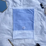 sac à chaussures / rangement, broderie anglaise et popeline vichy bleu, posé à plat sur un drap
