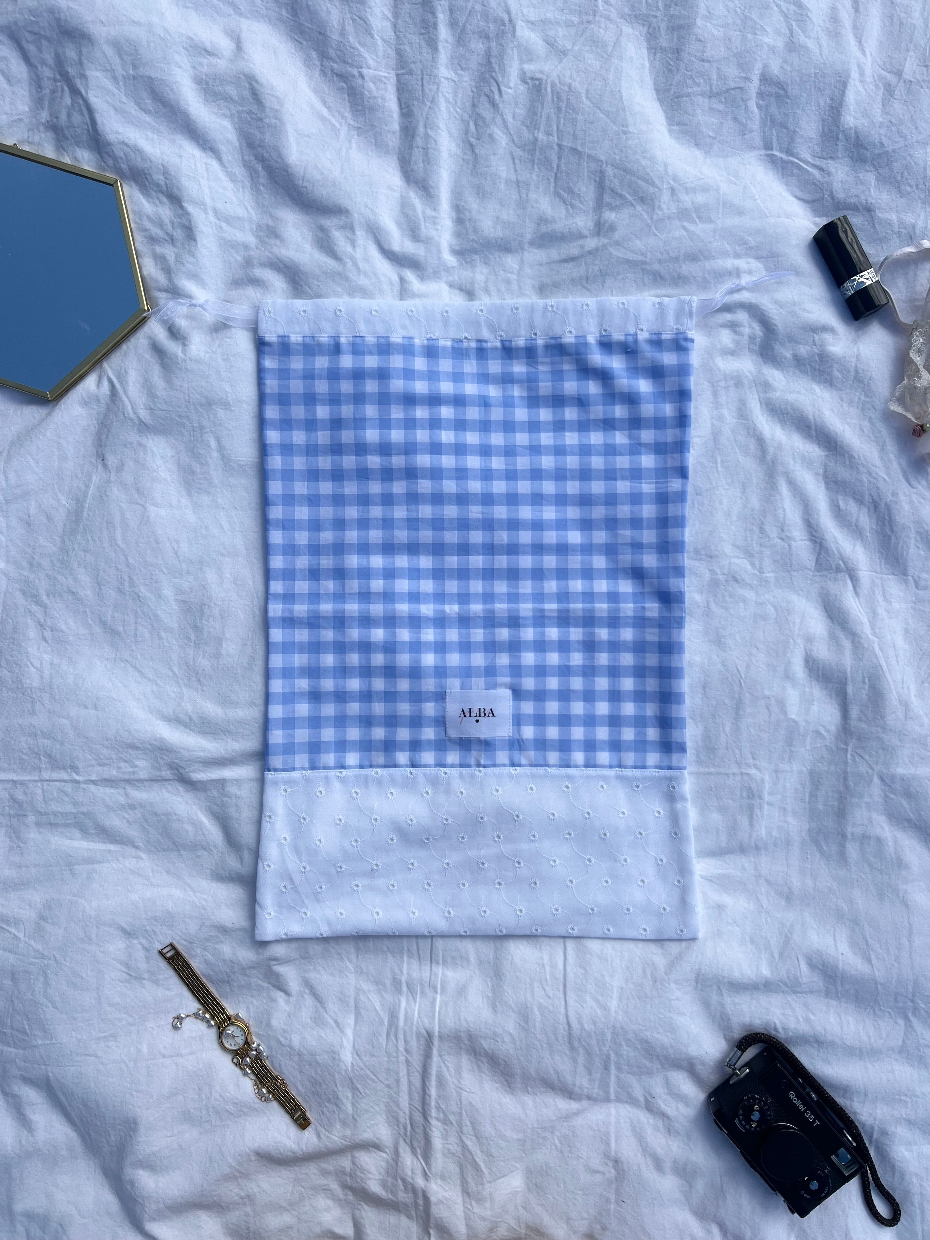 sac à chaussures / rangement, broderie anglaise et popeline vichy bleu, posé à plat sur un drap