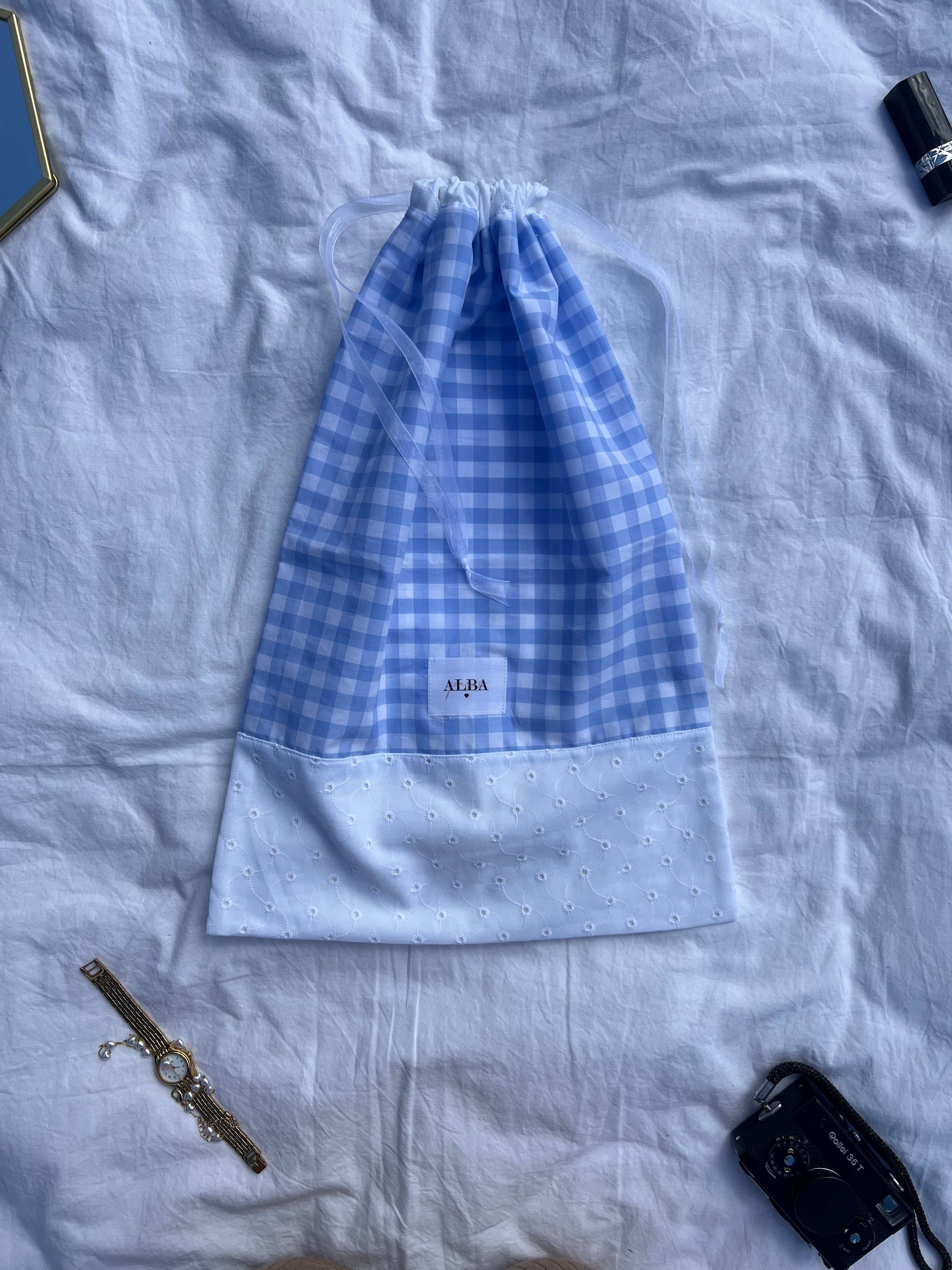 sac à chaussures / rangement, broderie anglaise et popeline vichy bleu, fermé et posé sur un drap