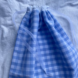 zoom détails sac à chaussures / rangement, broderie anglaise et popeline vichy bleu, fermé et posé sur un drap