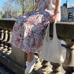 sac mael en dentelle blanche porté à la main avec robe simone à fleurs spring assis en extérieur 