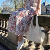 sac mael en dentelle blanche porté à la main avec robe simone à fleurs spring assis en extérieur 