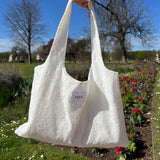 sac mael en dentelle blanche porté à la main en extérieur vue de près