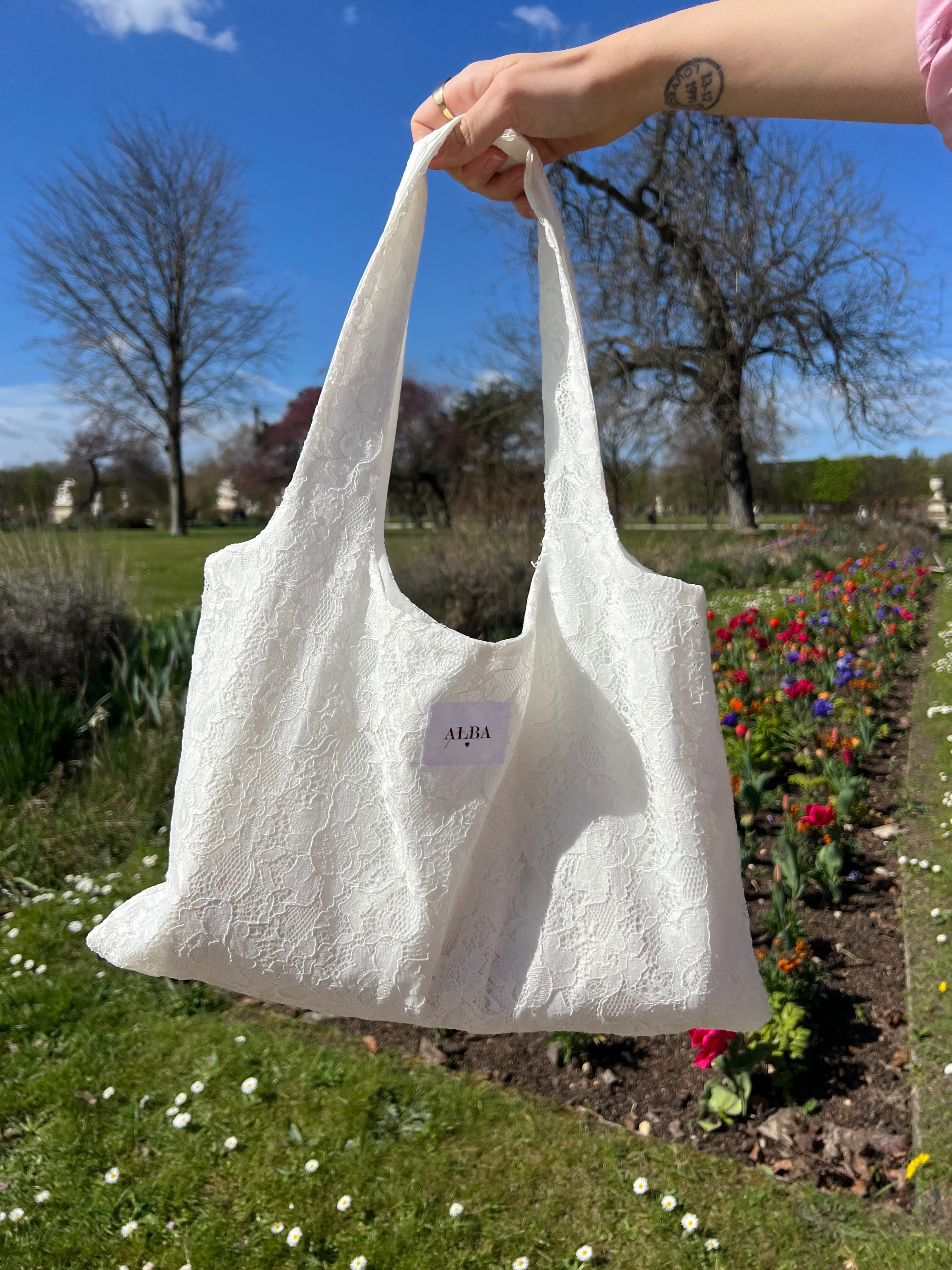 sac mael en dentelle blanche porté à la main en extérieur vue de près