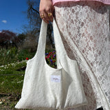 sac mael en dentelle blanche porté à la main en extérieur avec jupe en dentelle jeanne, vue de près