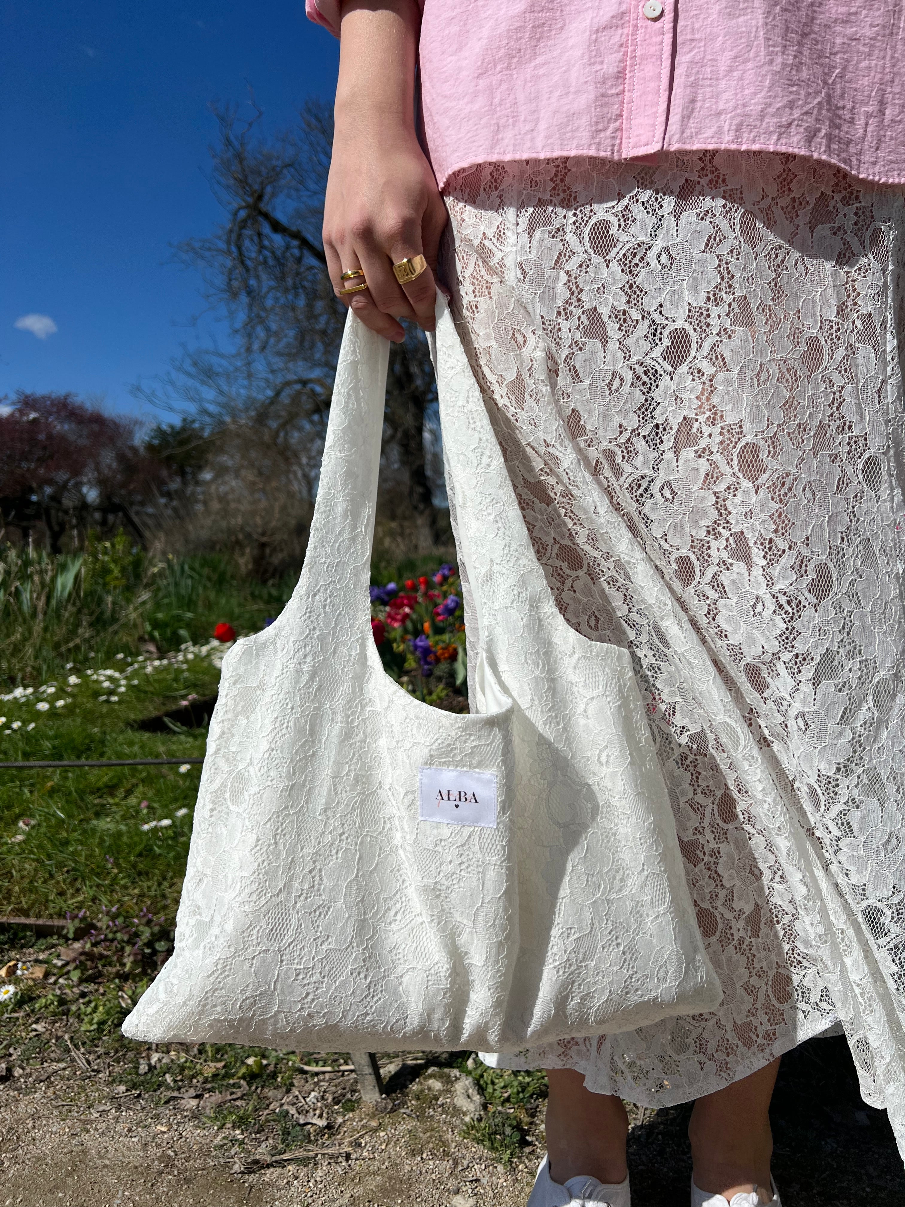 sac mael en dentelle blanche porté à la main en extérieur avec jupe en dentelle jeanne, vue de près