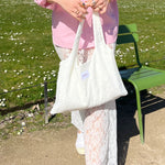 sac mael en dentelle blanche porté à la main en extérieur avec chemise rose et jupe jeanne en dentelle