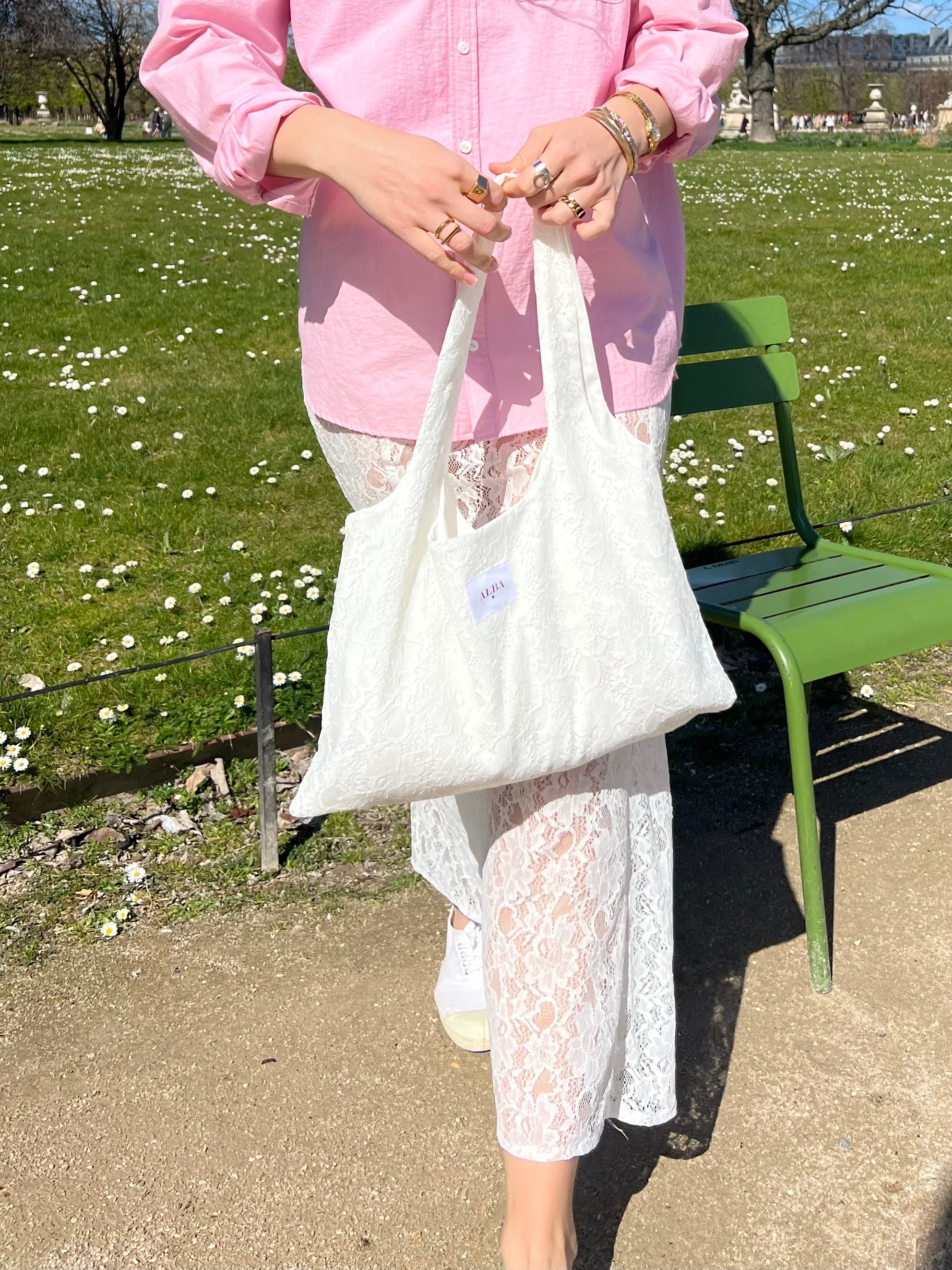 sac mael en dentelle blanche porté à la main en extérieur avec chemise rose et jupe jeanne en dentelle