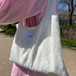 sac mael en dentelle blanche porté à l'épaule en extérieur avec jupe en dentelle et chemise rose zoom
