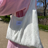 sac mael en dentelle blanche porté à l'épaule en extérieur avec jupe en dentelle et chemise rose zoom