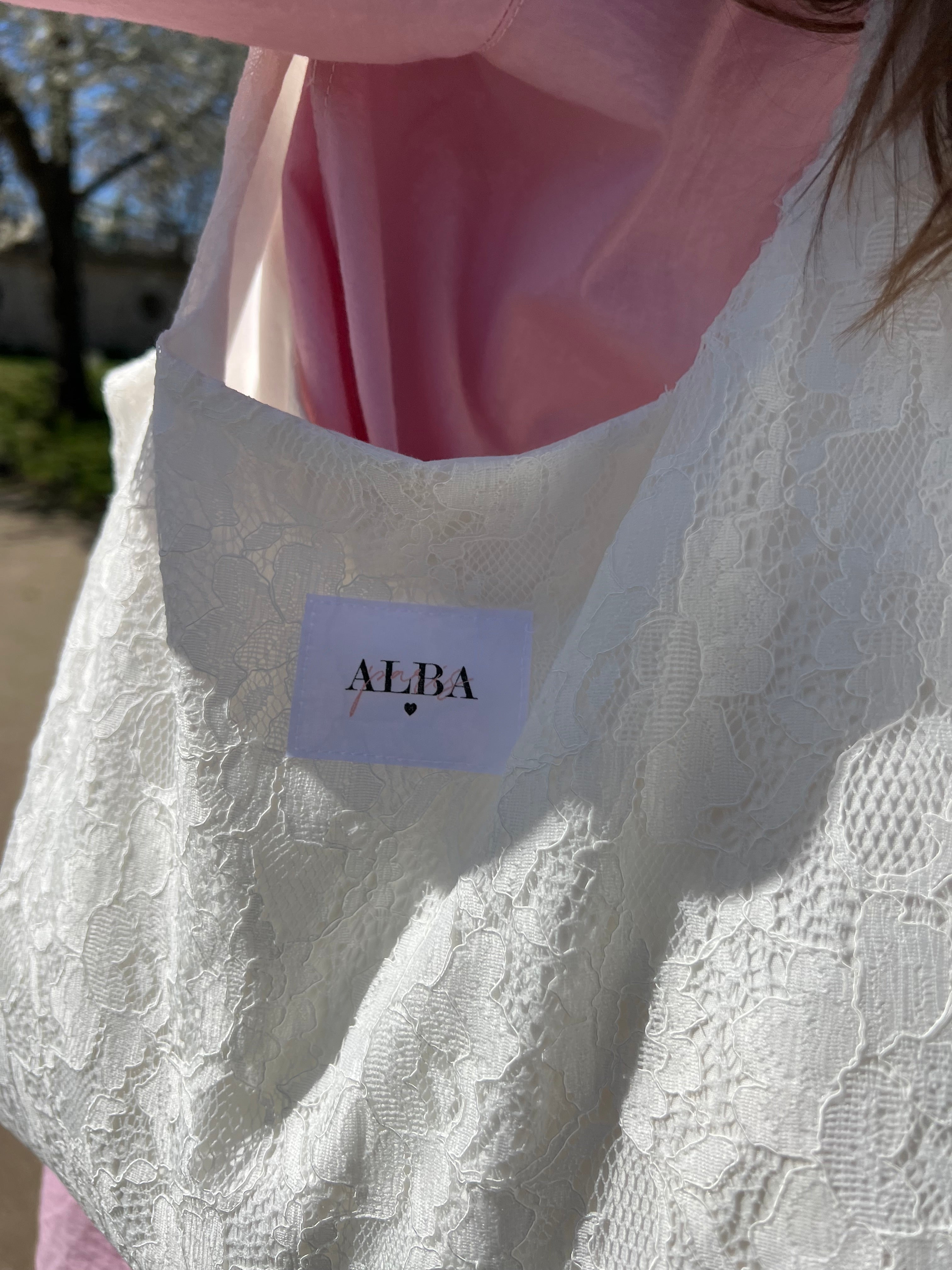 sac mael en dentelle blanche porté à l'épaule en extérieur avec chemise rose zoom