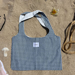 sac Maël en popeline vichy vert et blanc posé sur le sable vue de face