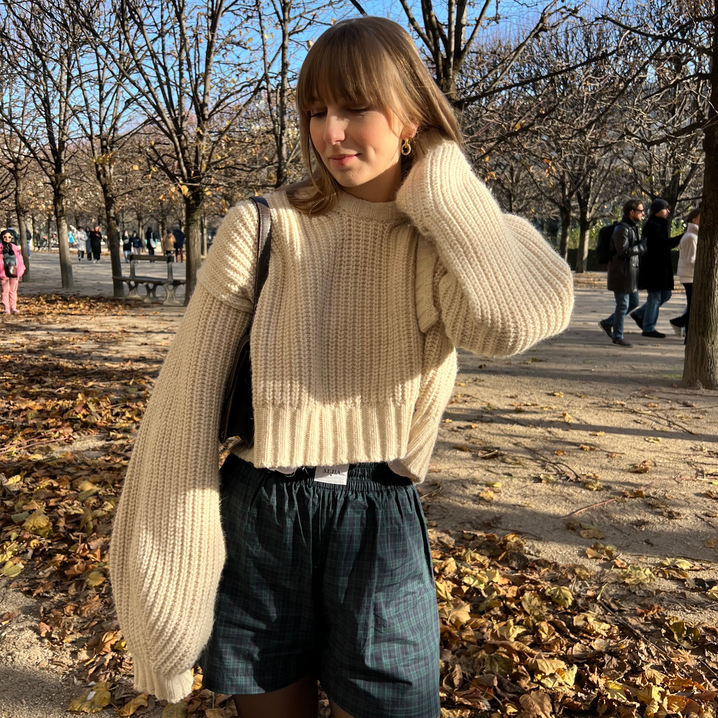 Short lucas en popeline à carreaux vert et bleu porté avec un pull beige