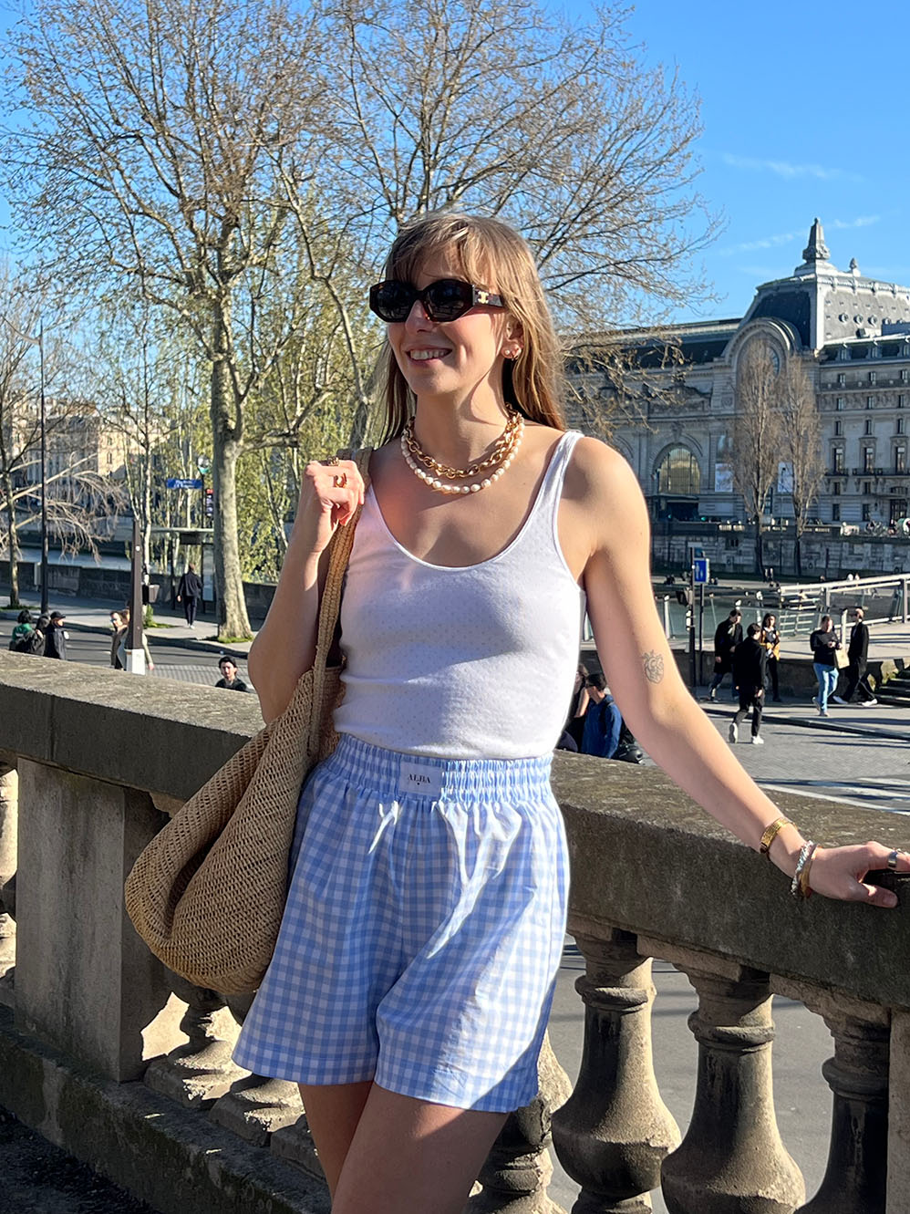 short lucas en popeline vichy bleu porté en extérieur avec un débardeur blanc et un sac
