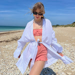 short Paul en jersey pointelle corail porté avec brassière Pauline en jersey pointelle corail et kimono Marcia en coton gaze blanc à la plage